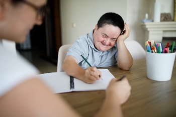 Heilpädagogin unterstützt Klientin mit Down Syndrom beim Schreiben