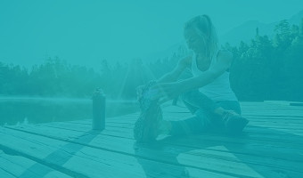Sportpsychologie studium Teaser Eine Frau ruht sich auf einem Steg am Wasser aus