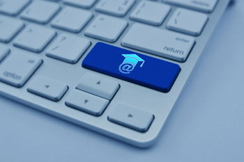 Eine Tastatur hat eine blau eingefärbte Taste, auf der das @-Zeichen mit einem Uni-Hut abgebildet ist.