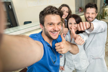 Pflegestudenten machen ein Selfie und halten lächelnd den Daumen nach oben 