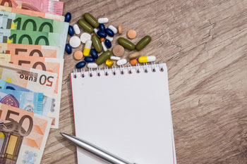 Geldscheine, Notizblock und Medikamente liegen auf einem Tisch