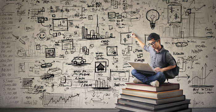 Ein Junge sitzt auf einem Stapel Bücher und malt mit dem rechten Arm an eine Wand hinter sich Skizzen.