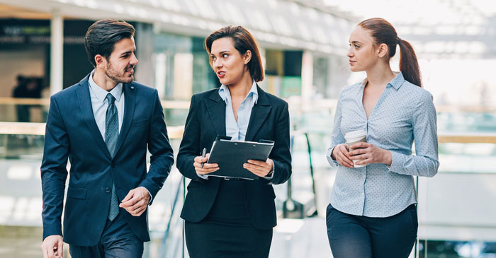 Ein dualer Student läuft mit zwei Kolleginnen durch das Unternehmen.
