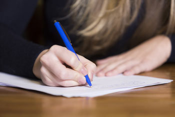 Abiturientin formuliert handschriftlich ein Motivationsschreiben zur Probe