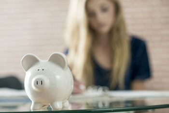 Eine Studentin sitzt vor einem weißen Sparschwein