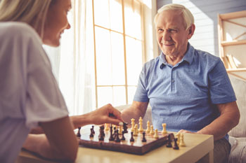 Eine Sozialarbeiterin spielt mit einem älteren Herren Schach.