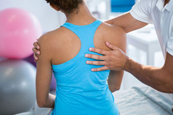 Ein Physiotherapeut richtet einer Patientin die Schulter