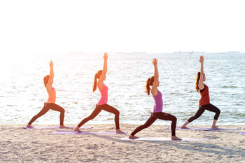 Eine Gruppe junger Frauen macht Sport am Strand, um gesund zu bleiben